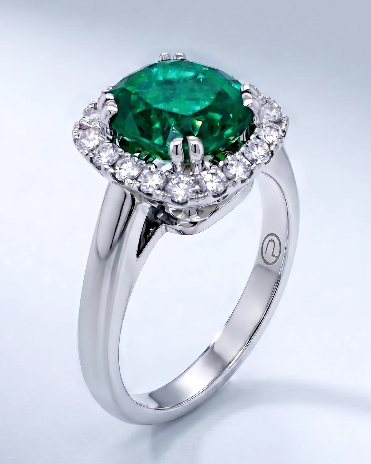 A cushion-cut Colombian emerald ring in platinum 950 with an old-mine diamond halo